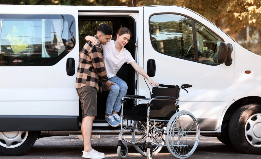 man helpt vrouw met rolstoel uit een autobus
