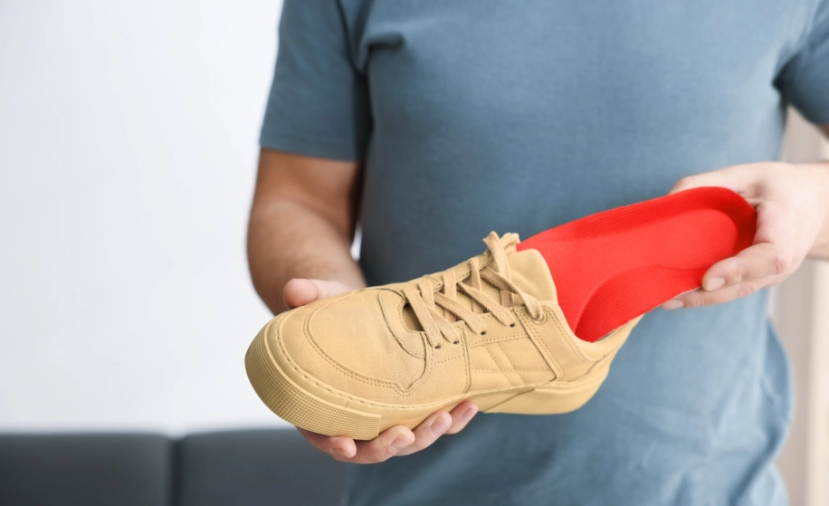 man houdt schoen met rode steunzool vast