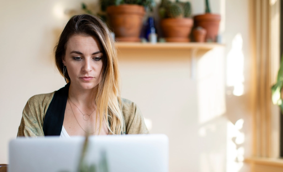 Vrouw die thuis naar haar laptop kijkt
