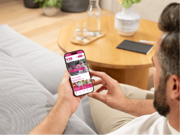 Man zit in zijn zetel en heeft de VNZ app open op zijn smartphone