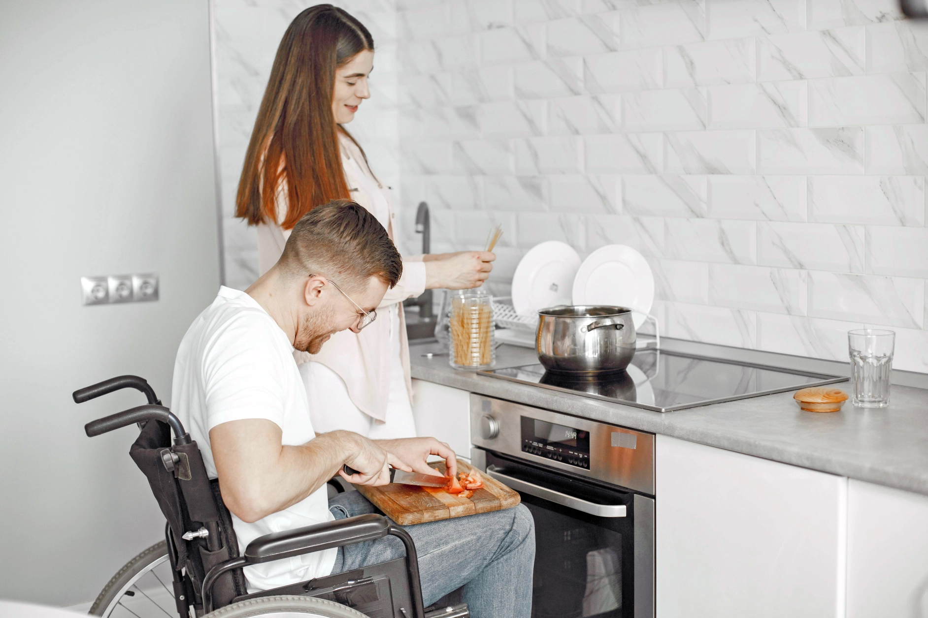 Man in rolstoel geholpen in de keuken